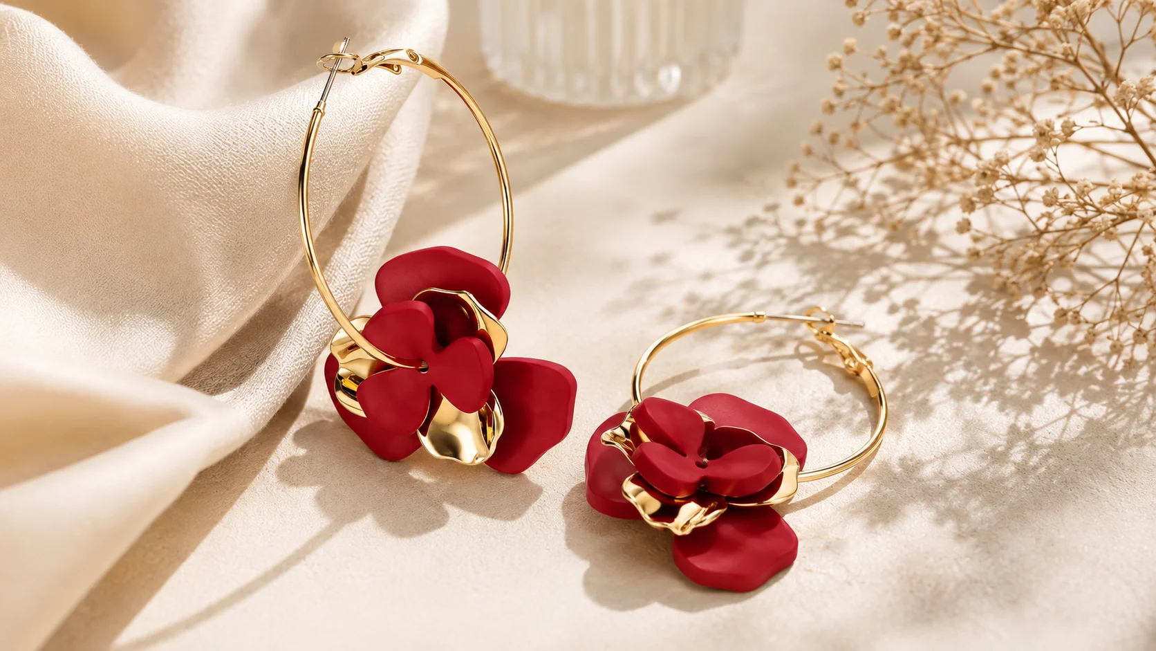 Statement hoop earrings with red floral detailing and golden-tone hoops styled in an elegant editorial jewellery composition.