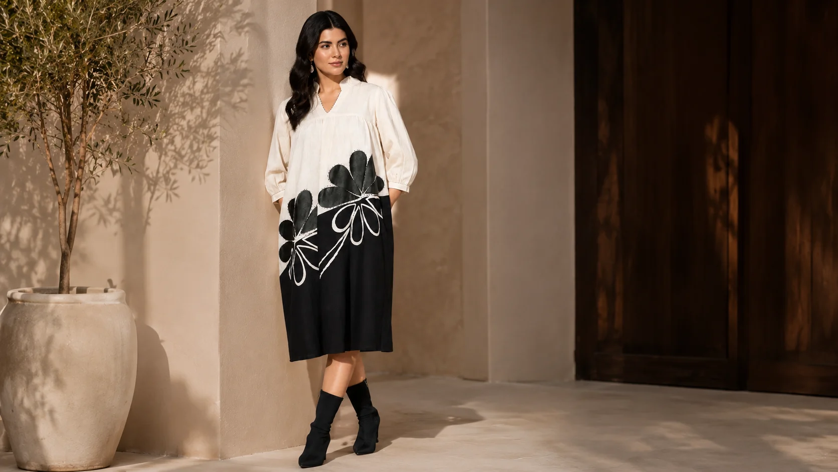 Woman wearing a black and white floral statement dress styled with black ankle boots for black and white dress styling inspiration.