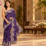 Purple embroidered saree with ornate border and unstitched blouse piece styled for an elegant occasion look